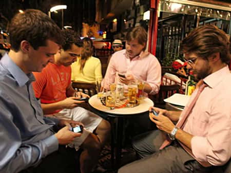 Amigos entretidos com celulares na mesa de bar